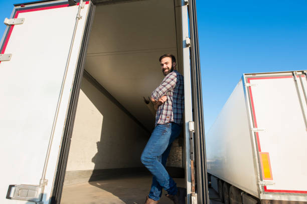truck driver standing in an empty truck trailer. trucker lifestyle and transportation services. - fechar porta bagagens imagens e fotografias de stock