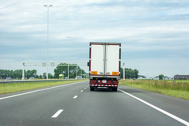 Truck  on highway (right drive) Rear view  of Truck on highway on a quiet day. No traffic jams expected. Same truck with digital sign on the right with delay or no delay are also available semi truck back stock pictures, royalty-free photos & images