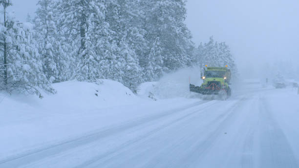 close up: грузовик пашет заснеженную променую дорогу во время ужасной метели. - blizzard стоковые фото и изображения