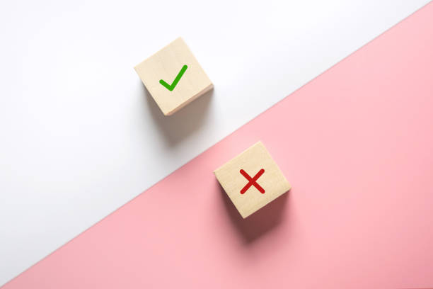 True and false symbols accept rejected for evaluation, Yes or No on wood blogs on pink and white background. True and false symbols accept rejected for evaluation, Yes or No on wood blogs on pink and white background. imitation stock pictures, royalty-free photos & images