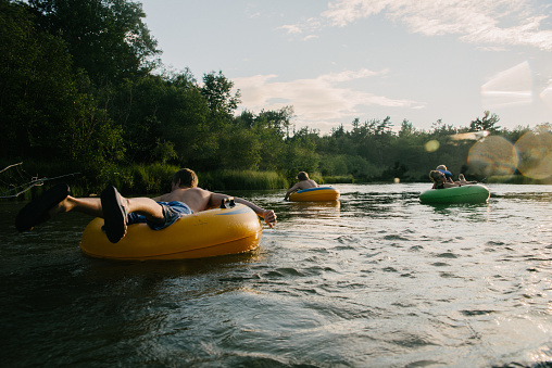 Young people floating down river in inner tubes