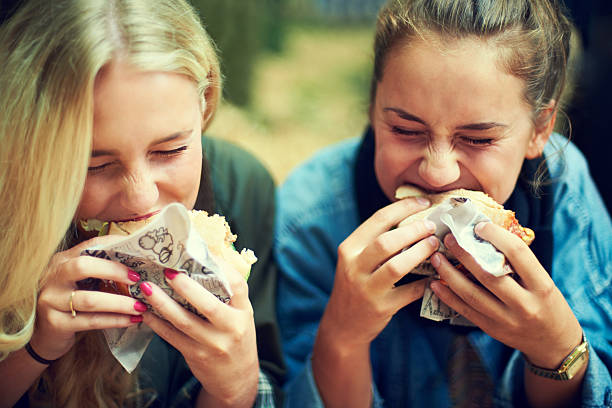 Tucking into some tastiness Shot of two young women eating at an outdoor festival shawarma stock pictures, royalty-free photos & images