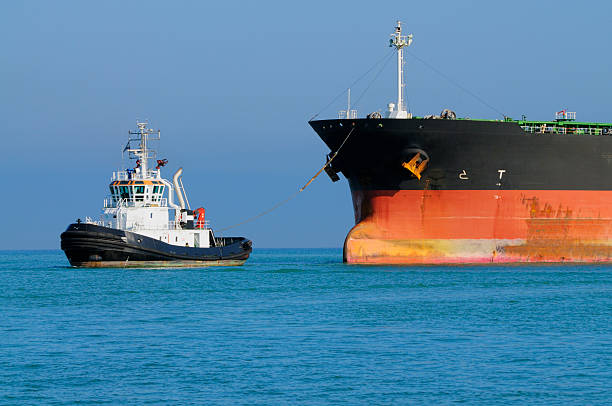 Tugboat Pulling Industrial Ship Industrial ship and tugboat barge stock pictures, royalty-free photos & images