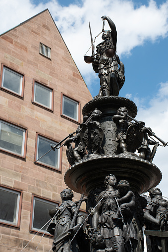 Nuremberg, Germany - July 3, 2021: The 16th-century Tugendbrunnen (Fountain of Virtues), a fountain depicting seven virtues, with justice on top, in Lorenzer Platz in the old town.