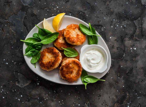Tuna and potato cutlets with spinach and greek yogurt on a dark background, top view stock photo