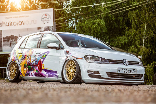 Tuned by low suspension and custom wide golden colored wheels. White volkswagen golf 7 with aerography on which painted Chip and Dale characters. stock photo