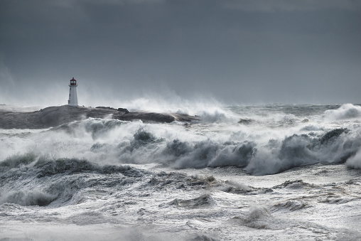 Waves break near the lighthouse at Peggy's Cove, Nova Scotia during a hurricane. Primary focus is on the water in the foreground.