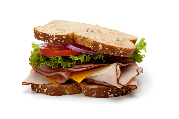 Turkey sandwich on whole-grain bread A turkey sandwich on a whole-grain bread with lettuce, cheese and tomatoes on a white background delicatessen stock pictures, royalty-free photos & images