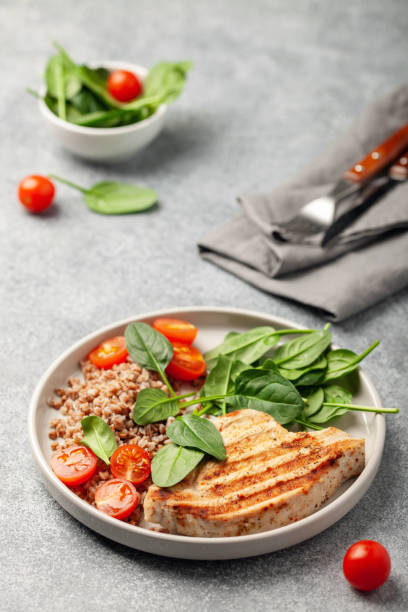 Turkey steak or chicken with buckwheat and spinach leaf salad and tomatoes.  Diet food. stock photo