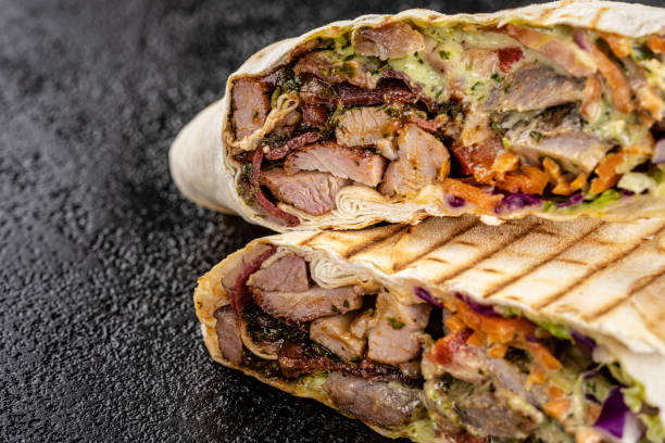 Turkish oriental cuisine. Grilled kebab with lamb, tomatoes, carrots, wrapped in thin pita bread. stock photo