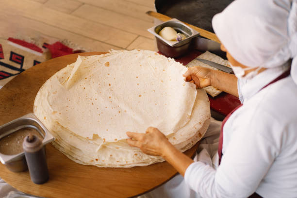 turkish woman making tortillas on a wooden rustic table. - idosos aquecedor imagens e fotografias de stock