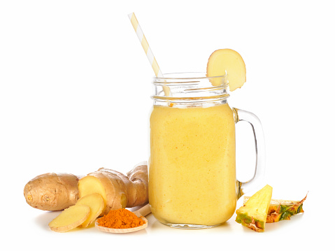 Turmeric, ginger and pineapple smoothie in a mason jar with ingredients isolated on a white background. Healthy immune boosting, weight loss, anti-inflammatory.