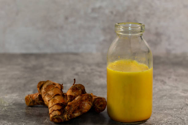 Turmeric root and golden milk against a grey background stock photo