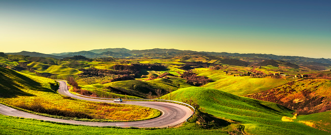 Tuscany landscape, hairpin bend road and green field at sunrise. Volterra Italy Europe