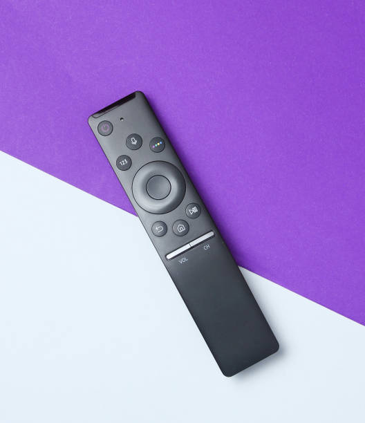 tv Modern smart tv remote on gray-purple paper background. Top view. Minimalism remote control stock pictures, royalty-free photos & images