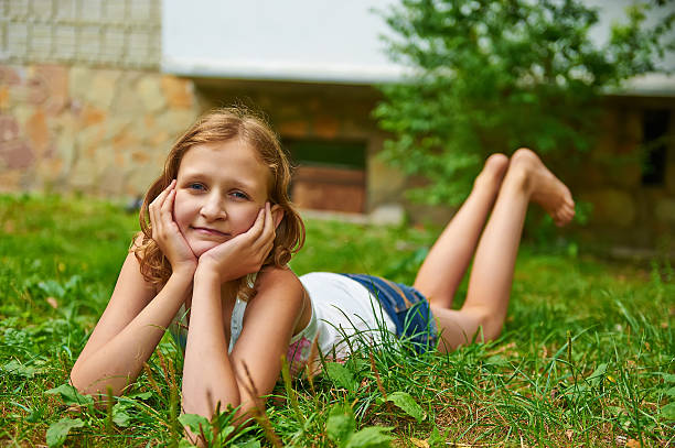 Twelve year old girl lies on the grass and smiling stock photo