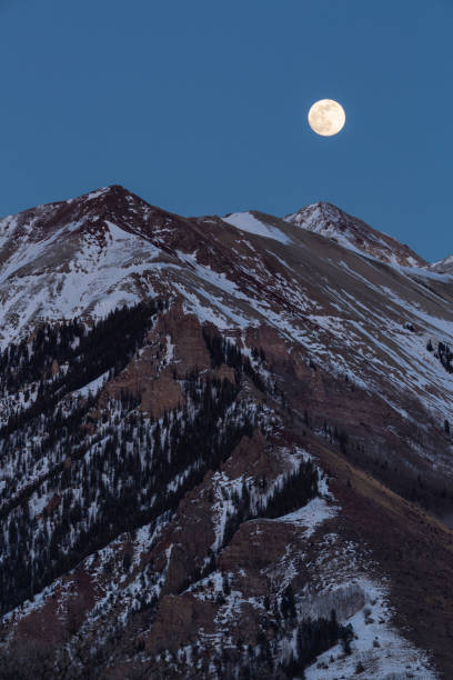 Twilight Moon Over Snowy Peaks stock photo