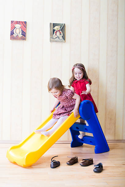 Two adorable girls having fun atop playground slide stock photo