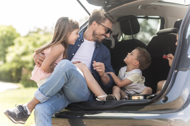 two adorable kids sitting in a trunk car with father - family car imagens e fotografias de stock