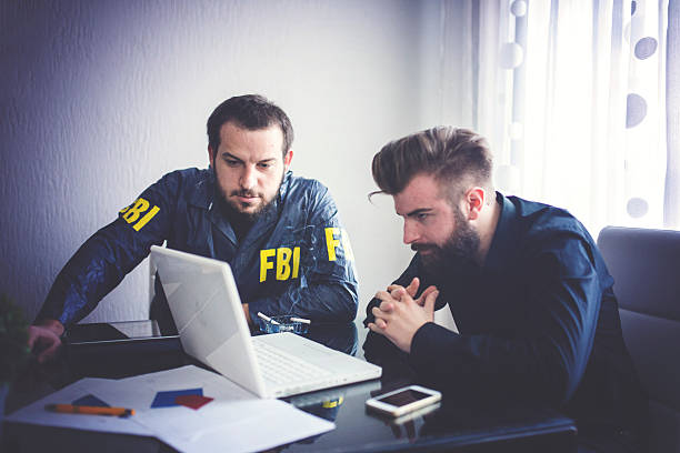 два агентов смотрит на ноутбук - fbi стоковые фото и изображения