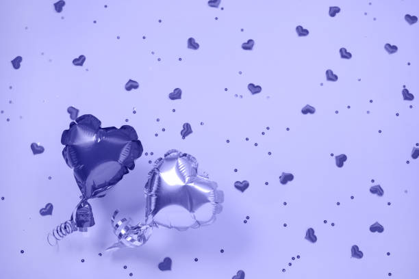 Two Air Balloons of heart shaped foil on festive violet color. stock photo