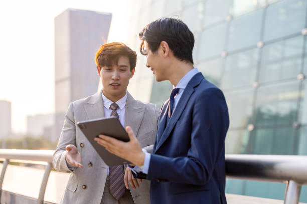 Two Asian businessmen are talking outdoors stock photo