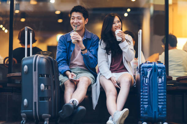 Two asian tourists with suitcases spending happy time in cafe Two Asia tourists are drinking coffee happy in a cafe in their travel destination. japan travel stock pictures, royalty-free photos & images