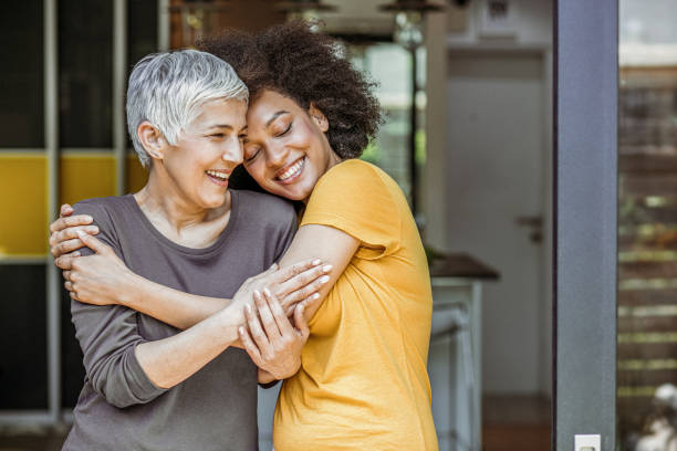 Two beautiful woman embracing Happy loving caucasian woman and grown millennial african woman laughing embracing. affectionate stock pictures, royalty-free photos & images