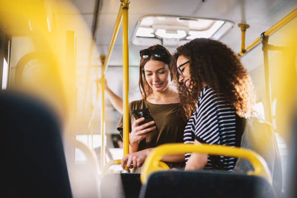 Two best young sweet girl friends standing in a bus and looking in a telephone.  commercial land vehicle stock pictures, royalty-free photos & images
