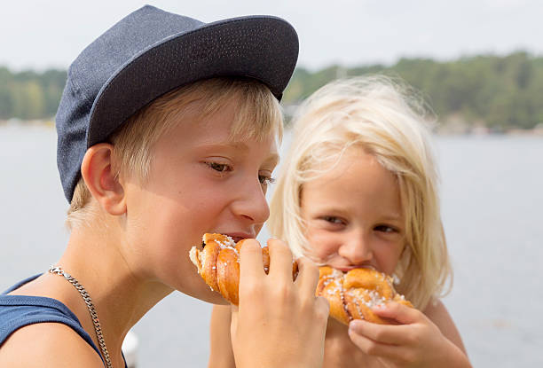 Two blond boys eating cinnamon buns stock photo