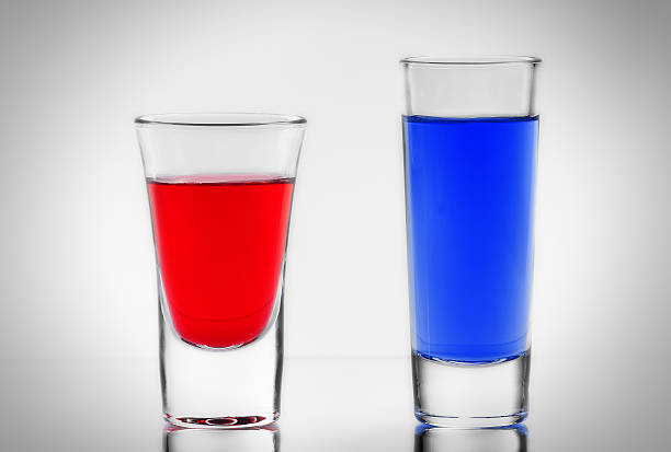 Two blue and red cocktail in full transparent shot glasses the two blue and red cocktail in full transparent shot glasses with own reflections bar drink establishment stock pictures, royalty-free photos & images