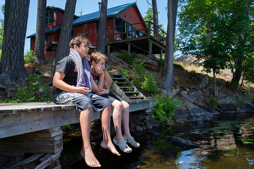Two bothers relaxing on the dock of an island cabin or cottage.