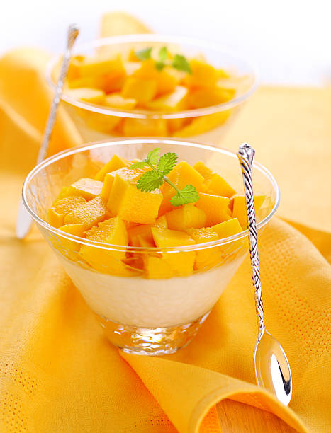Two bowls full of a mango dessert on a yellow table cloth stock photo