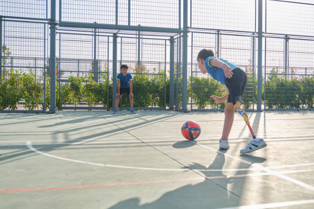 Two brothers playing football, one has a prosthesis and is kicking a penalty. stock photo