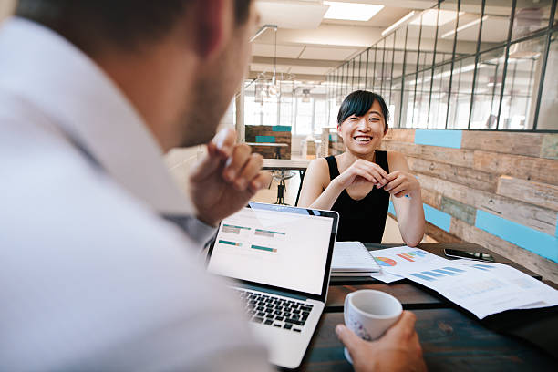 Two business colleagues discussing work in office Shot of two business colleagues discussing work in office. Smiling young asian woman meeting with office manager. jacob ammentorp lund stock pictures, royalty-free photos & images
