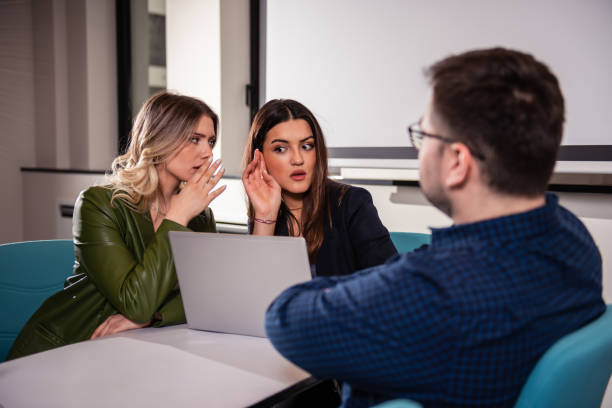 two business women gossip about their colleague at a business meeting - uitdagend stockfoto's en -beelden