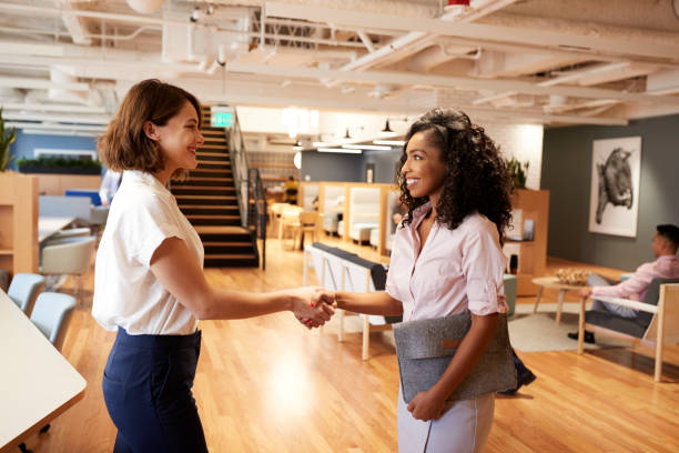 Two Businesswomen Meeting And Shaking Hands In Modern Open Plan Office Two Businesswomen Meeting And Shaking Hands In Modern Open Plan Office job interview stock pictures, royalty-free photos & images