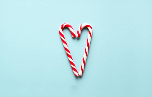 Two candy canes laid  in shape of heart on blue. stock photo
