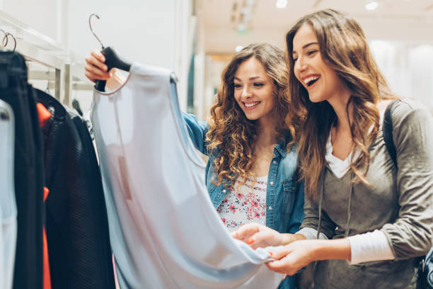 Two cheerful girls shopping for clothes Two young women in the fashion store boutique stock pictures, royalty-free photos & images