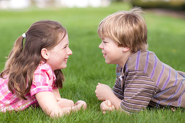Two children laughing together on grass (Series) stock photo