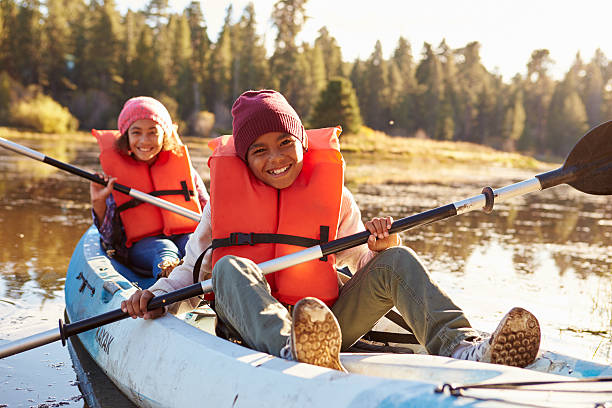 two children rowing kayak on lake - kajak stockfoto's en -beelden