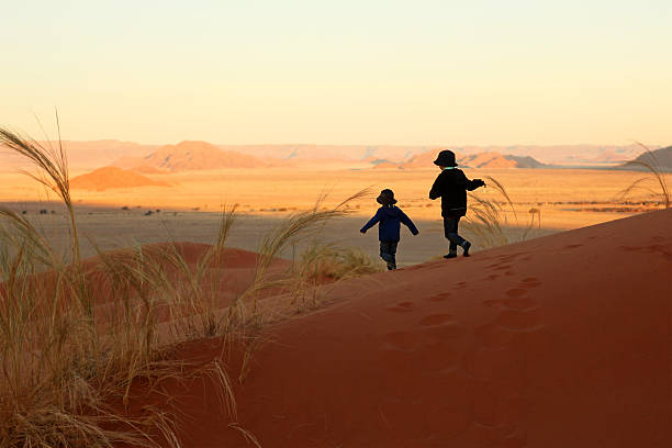 Two Children Running Down The Sand Dunes in Sossusvlei Namibia stock photo