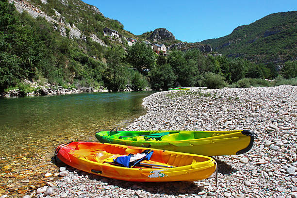 Two colorful canoes on the bank of the river Tarn Two colorful canoes abandoned for a moment on the rocky banks of the river Tarn in the Gorges du Tarn in the South of France. gorges du tarn stock pictures, royalty-free photos & images