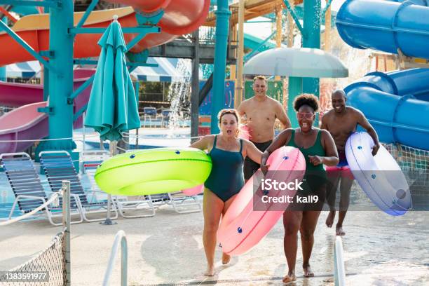 Two couples carrying inflatable rings to lazy river
