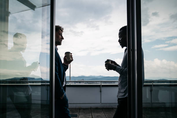 Two co-workers enjyoing a coffee break on a terrace stock photo