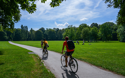Two cyclists on a asphalt cycling lane in the English garden, a famous park in the centre of Munich, Germany