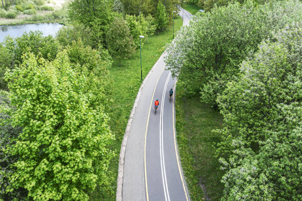 two cyclists ride bikes on bicycle path in city park at spring day. aerial photography with drone. stock photo