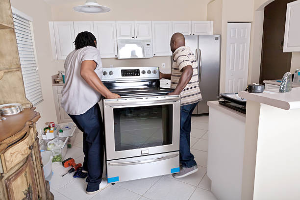 two delivery men installing an oven stock photo