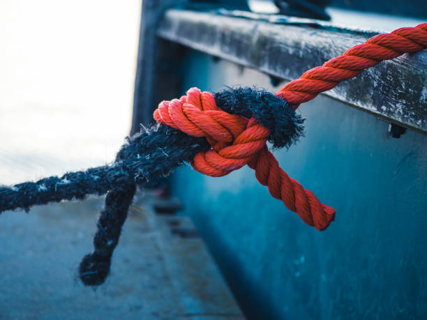 Two different colored ropes tied together at a mooring Two different colored ropes tied together at a mooring knotted wood stock pictures, royalty-free photos & images