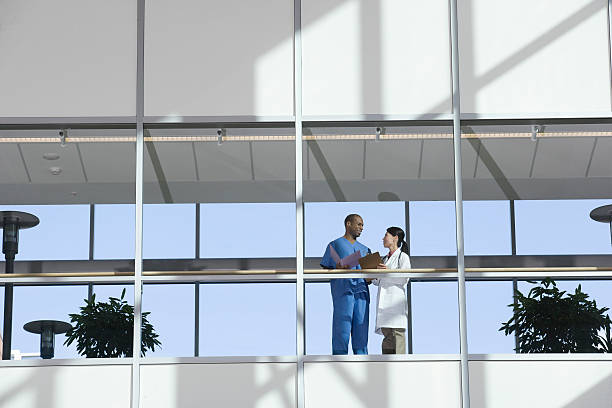 dos médicos hablando en pasillo - hospital building fotografías e imágenes de stock